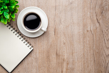 Flat lay, top view office table desk. Workspace with, laptop,office supplies, pencil, green leaf, and coffee cup on wood background.