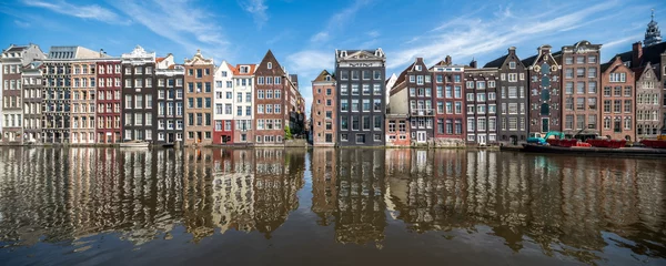 Fototapeten Panoramic view of traditional houses along the Damrak canal in Amsterdam, Netherlands © eyetronic