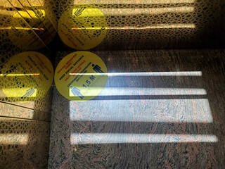Background with yellow sticker warning of social distance in Turkish, English, German, Russian. Caution sign on marble floor with striped shadows and reflections in corner. Text - keep social distance
