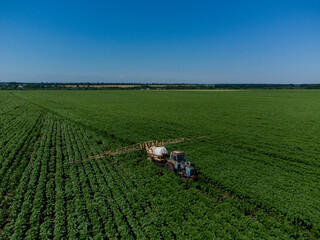 Tractor with a sprayer on a sun field. Application of herbicides.