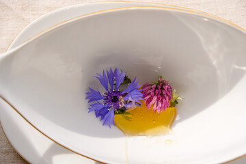 Honey with meadow flowers in a white porcelain cup. Natural light. 