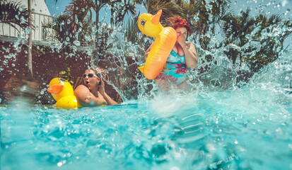 Beautiful young fat woman is jumping splash into the summer water pool with yellow duck lifebuo 
