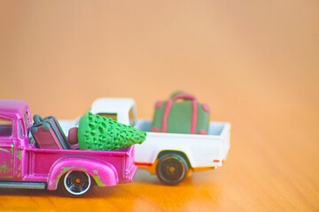 Car toy models with suitcases and christmas tree. Miniature fir and briefcases made of polymer clay. Concept of festival travel and vacation. Small purple and white pickup automobiles on table.