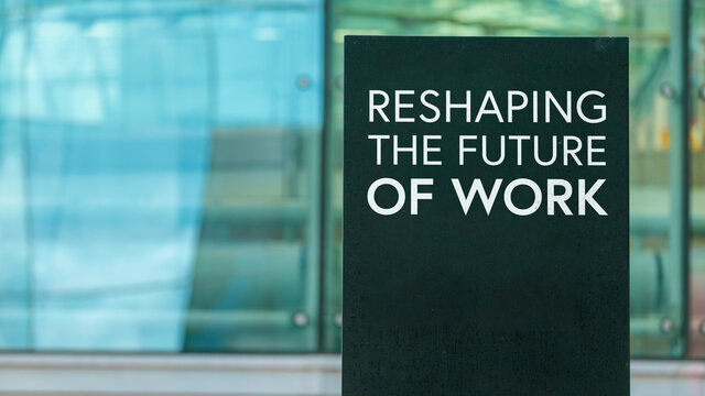 Reshaping the future of work on a city-center sign in front of a modern office building	
