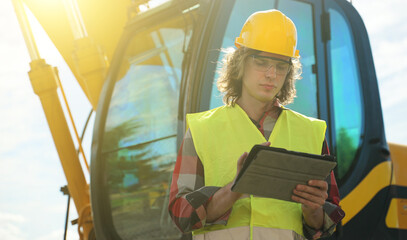 Excavator operator in hard hat using tablet pc.