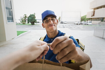 African american delivery man delivering fast food meal package in paper bag from cafeteria restaurant - Focus on face