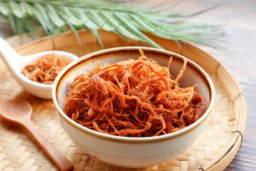 Fried shredded pork in white bowl of bamboo basket - Thai food called Moo Foi at close up view