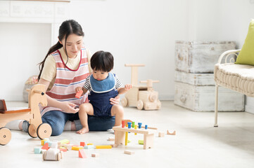 保育士さんとお世話される赤ちゃん　広角　右にコピースペースあり
