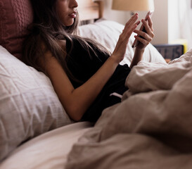 Obraz na płótnie Canvas Woman using her phone in bed