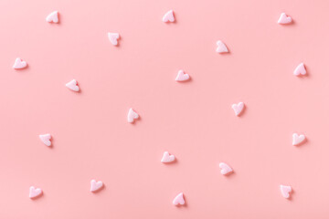 sweet sprinkles of heart shapes over pink background, concept of festive invitation for Valentines...