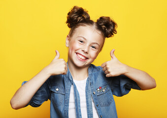 beautiful and confident girl showing thumbs up isolated over yellow background