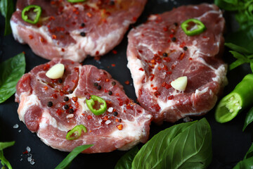 Fresh raw meat steak with spices and fresh basil.