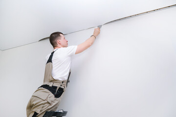 worker installs a stretch ceiling. Construction and renovation