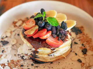 Pancakes with berries and fruits on a white plate