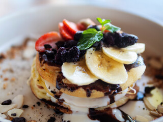 Pancakes with berries and fruits on a white plate