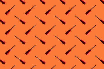Screwdrivers on an orange background, pattern, hard shadows. Construction tools, repairs. Background for the design.