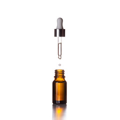 A glass jar and a flying dropper with a drop on a white background. Cosmetics, skin care.