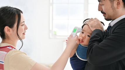 保育園の登園で体温計で検温される赤ちゃん