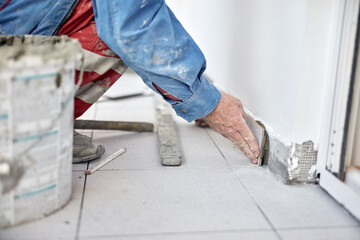 Professional ceramics tile man worker placing new tiles on the floor and wall.