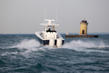 center console boat speeding past a lighthouse.