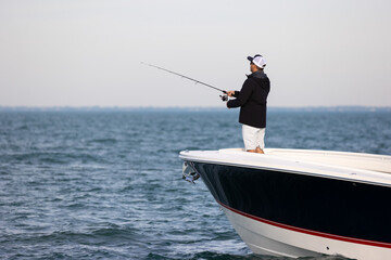 person fishing from the bow of a boat on the sea