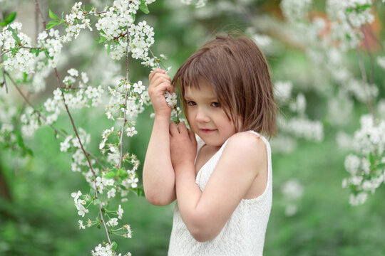 Adorable European kid girl with cherry blossom flowers, spring and self-care, tender child girl photo, childhood