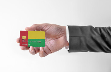 Bank credit plastic card with flag of Guinea Bissau holding man in elegant suit