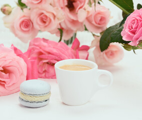 white ceramic cup with coffee and blue macaron on a white table