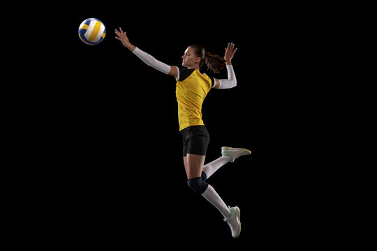 Female professional volleyball player with ball isolated on black studio background. The athlete, exercise, action, sport, healthy lifestyle, training, fitness concept.