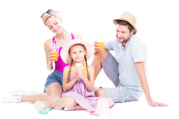 Horizontal studio portrait of family with cute daughter wearing summer outfits sitting on floor drinking juice and eating ice cream, white background