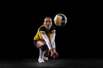 Fototapeta na wymiar Female professional volleyball player with ball isolated on black studio background. The athlete, exercise, action, sport, healthy lifestyle, training, fitness concept.