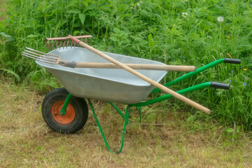 Green vegetable garden. Lawn. Mown grass. Garden wheelbarrow. Gardening Tools. Close-up.