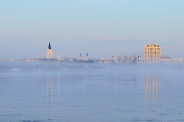 Morning fog over the river during flooding. The spire of the church.