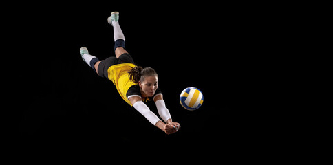 Female professional volleyball player with ball isolated on black studio background. The athlete,...