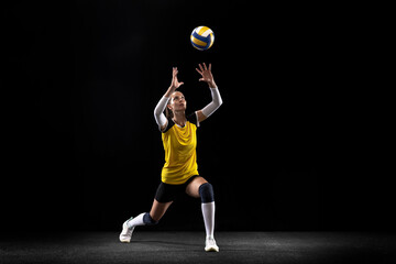Female professional volleyball player with ball isolated on black studio background. The athlete, exercise, action, sport, healthy lifestyle, training, fitness concept.