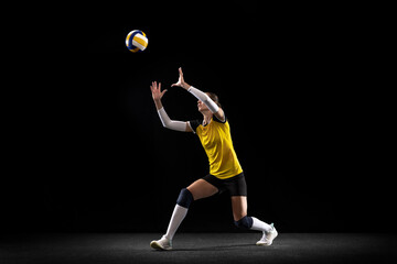 Female professional volleyball player with ball isolated on black studio background. The athlete,...