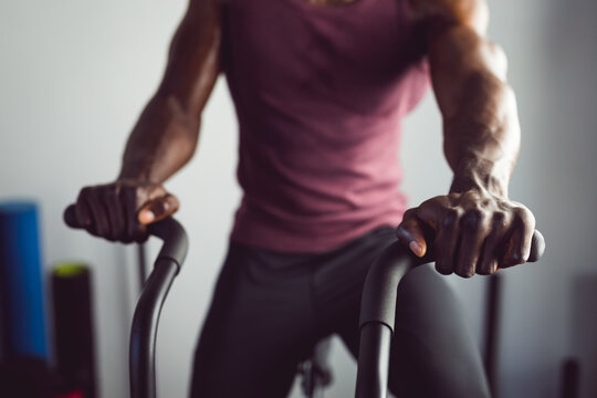 Midsection of african american man exercising at gym using rowing machine - Powered by Adobe
