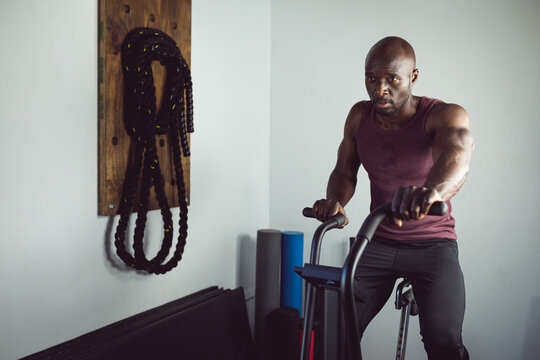 Fit african american man exercising at gym using rowing machine