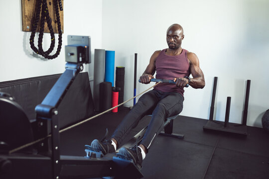 Fit african american man exercising at gym, using rowing machine
