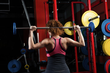 Fototapeta na wymiar Woman bodybuilder engaged with a barbell in the gym