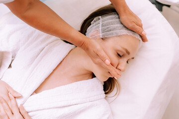 Close-up of young smiling young woman getting spa massage treatment at beauty spa salon. Spa skin and body care. Facial care. Cosmetology 