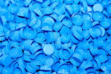 New blue plastic bottle caps as a background. Concept: plastic products, waste recycling