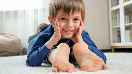 Portrait of happy smiling boy lying on mother's feet and looking in camera. Family having fun and playing together © Kyrylo Ryzhov