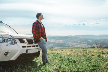 man standing near suv car at the top of the mountain