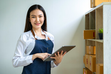 Starting small businesses SME owners female entrepreneurs Use a laptop or notebook to receive and review orders online to prepare to pack boxes, sell to customers, SME online business ideas.