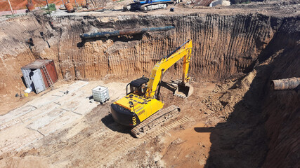Yellow industrial excavator working in the big pit on construction site