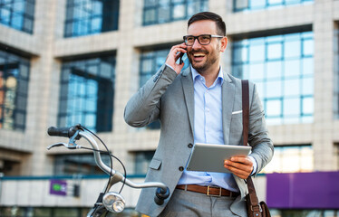 Businessman holding tablet and making a phone call in front of the corporation. Business, lifestyle concept