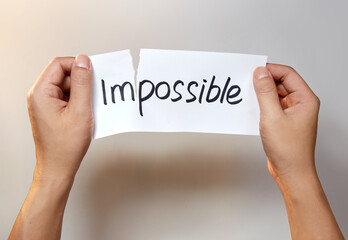 Hands tearing a white paper with the text impossible