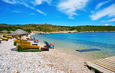 Fototapeta na wymiar Beach, sea and sunbeds at Demircili bay in Urla, İzmir, Turkey. Holiday or travel destinations.