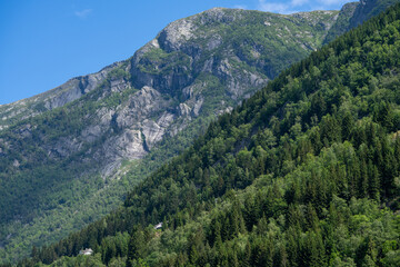 One of the mountains surrounding Odda in Hardanger, Norway. You can see some houses in the bottom left part of the photo, and shows how small houses are compared to that mountain.